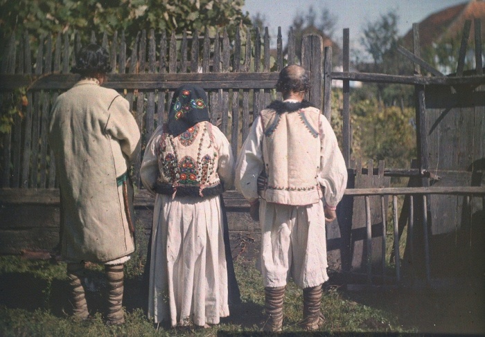 Romanian men in laced slippers and felt outerwear, Romanian woman in a leather waistcoat Tatárfalva, Romania. Taken by István Györffy, 1911, colour, autochrome plate, 13x18 cm.  Museum of Ethnography, D 4982