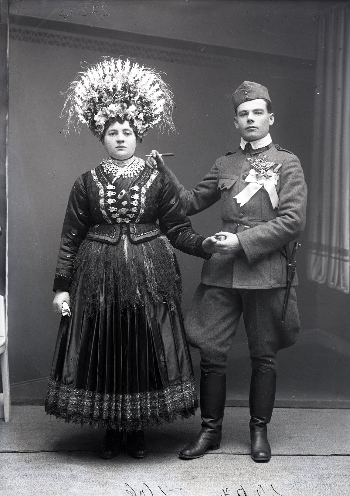 Esküvői kép, Széplaki Gáspár és menyasszonya. A menyasszony ünnepi vattás rékliben, színes koszorúban, a vőlegény katonaruhában, bokrétával, Mezőkövesd, üvegnegatív, 12x16,5 cm, Weissbach Rilly és testvére, 1915 körül, Néprajzi Múzeum, F 27234