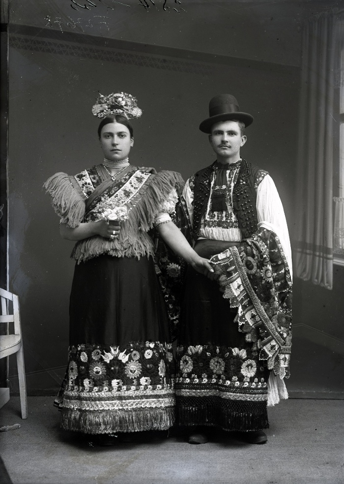 Fiatal házaspár, a fiatalasszony díszes újmenyecske főkötőben, melyet az esküvő után 1-2 évig hordtak, Mezőkövesd, üvegnegatív, 12x16,5 cm, Weissbach Rilly és testvére, 1910-es évek második fele, Néprajzi Múzeum, F 27678