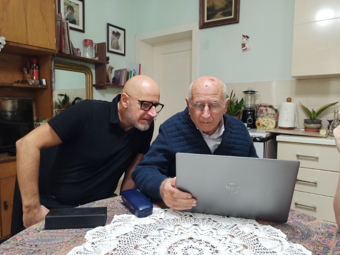 A Laca-család otthona, bal oldalt Kole Laca (dédunoka), mellette édesapja Tonin Laca (unoka), miközben gyűjtemény fotóit nézegetik. Shkodra, Albánia, 2024.